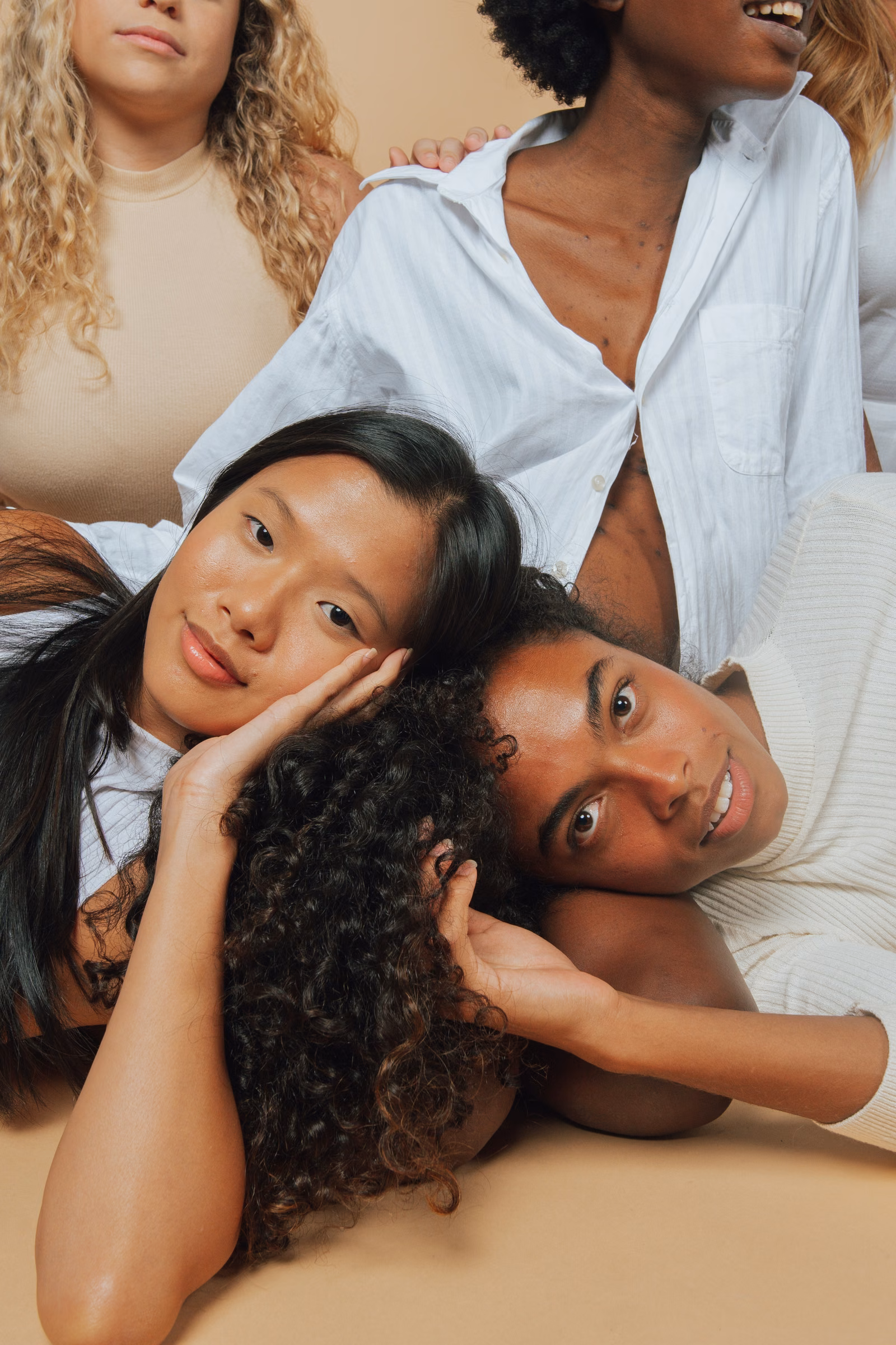 Four women lying close together, smiling at the camera